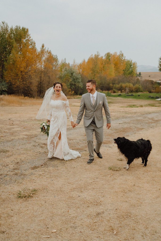 Bride + Groom laughing and walking in the Montana field. Photographed by Montana wedding photographer Ashley J Photography.